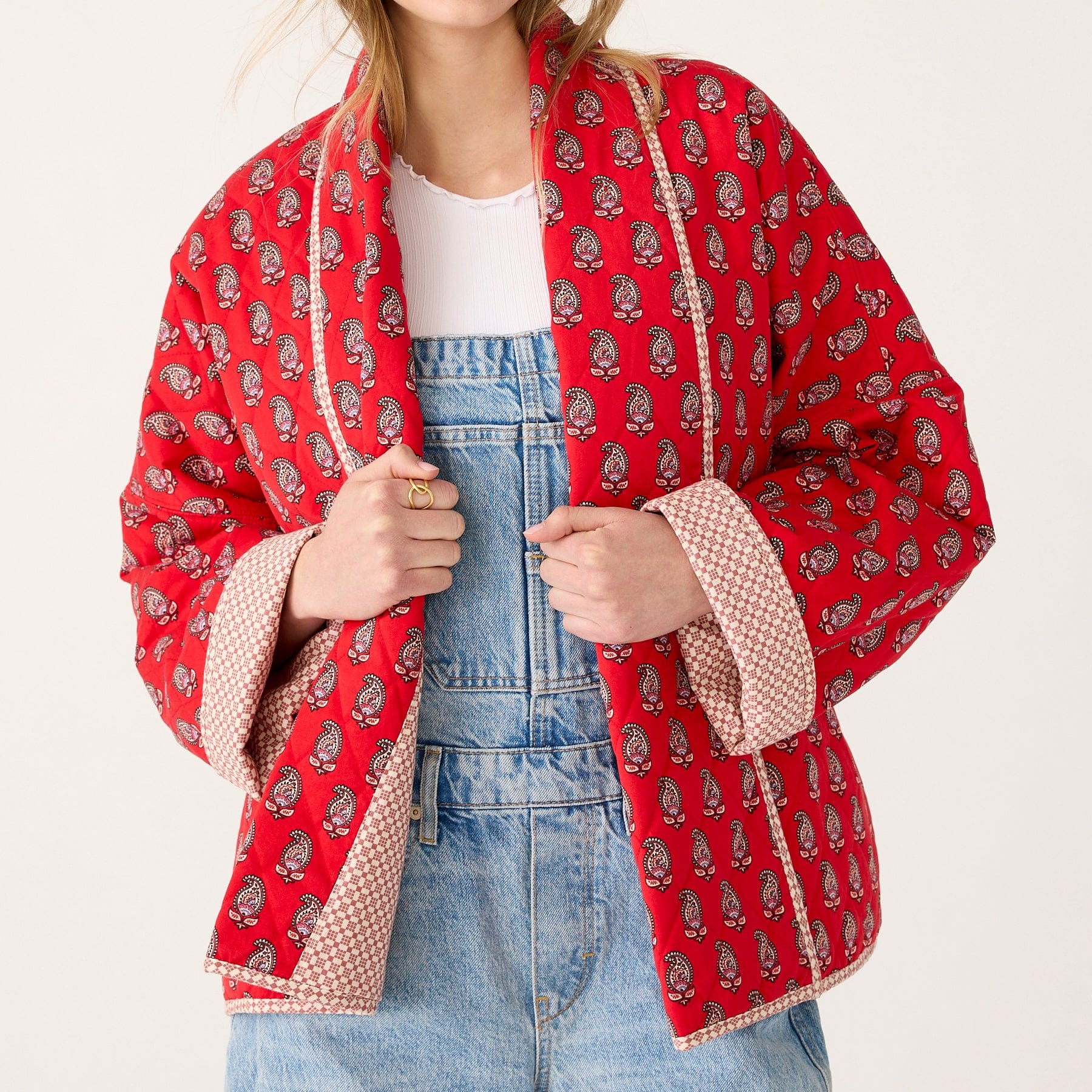 model wearing denim overalls and quilted jacket with red and paisley pattern
