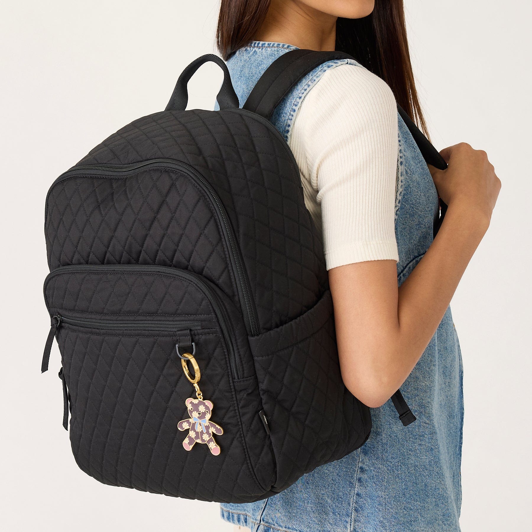 model wearing denim shirt with black quilted cotton backpack slung across shoulder